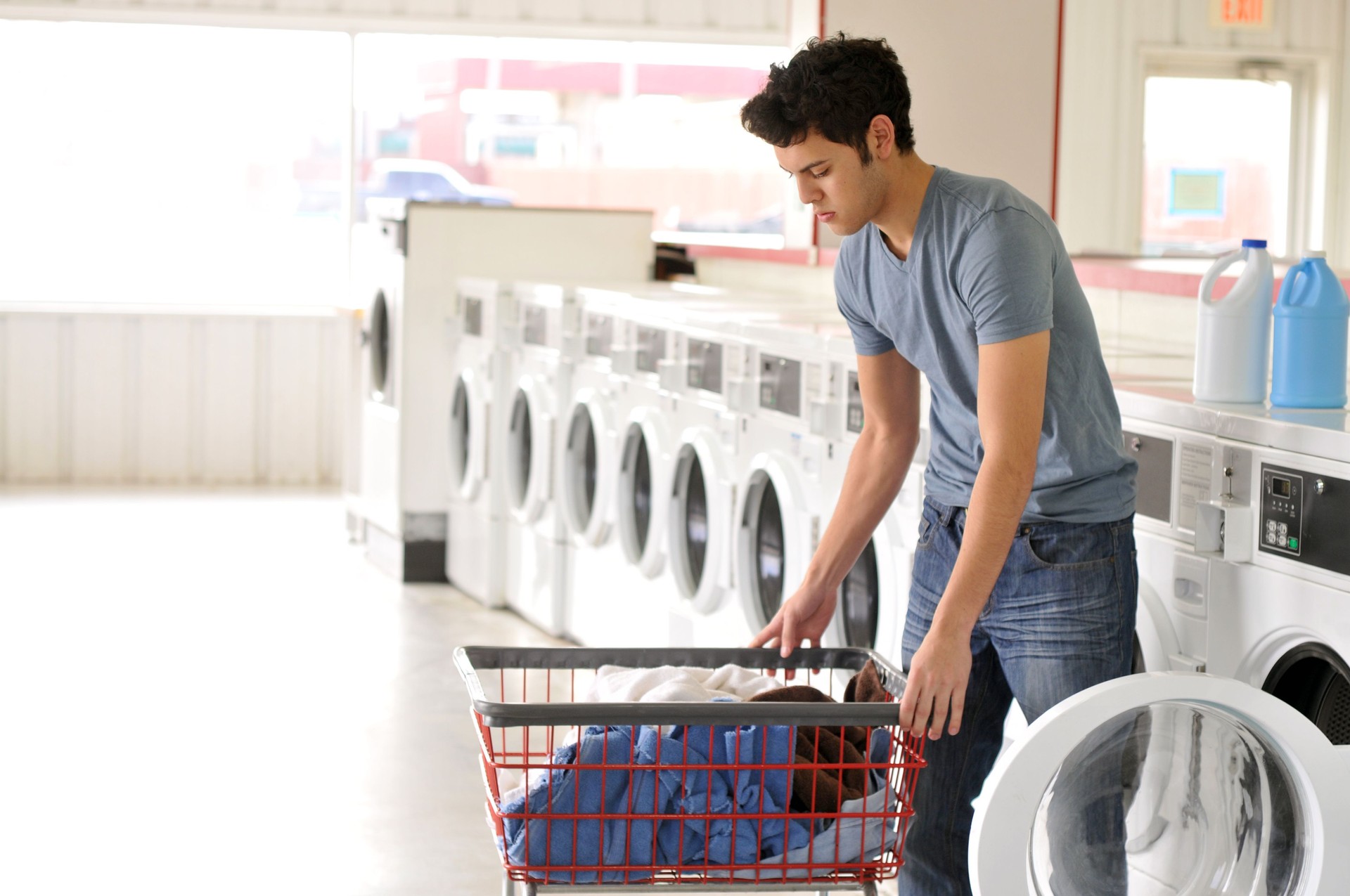 Hispanic Young Man at a Laundromat Washing His Clothes
