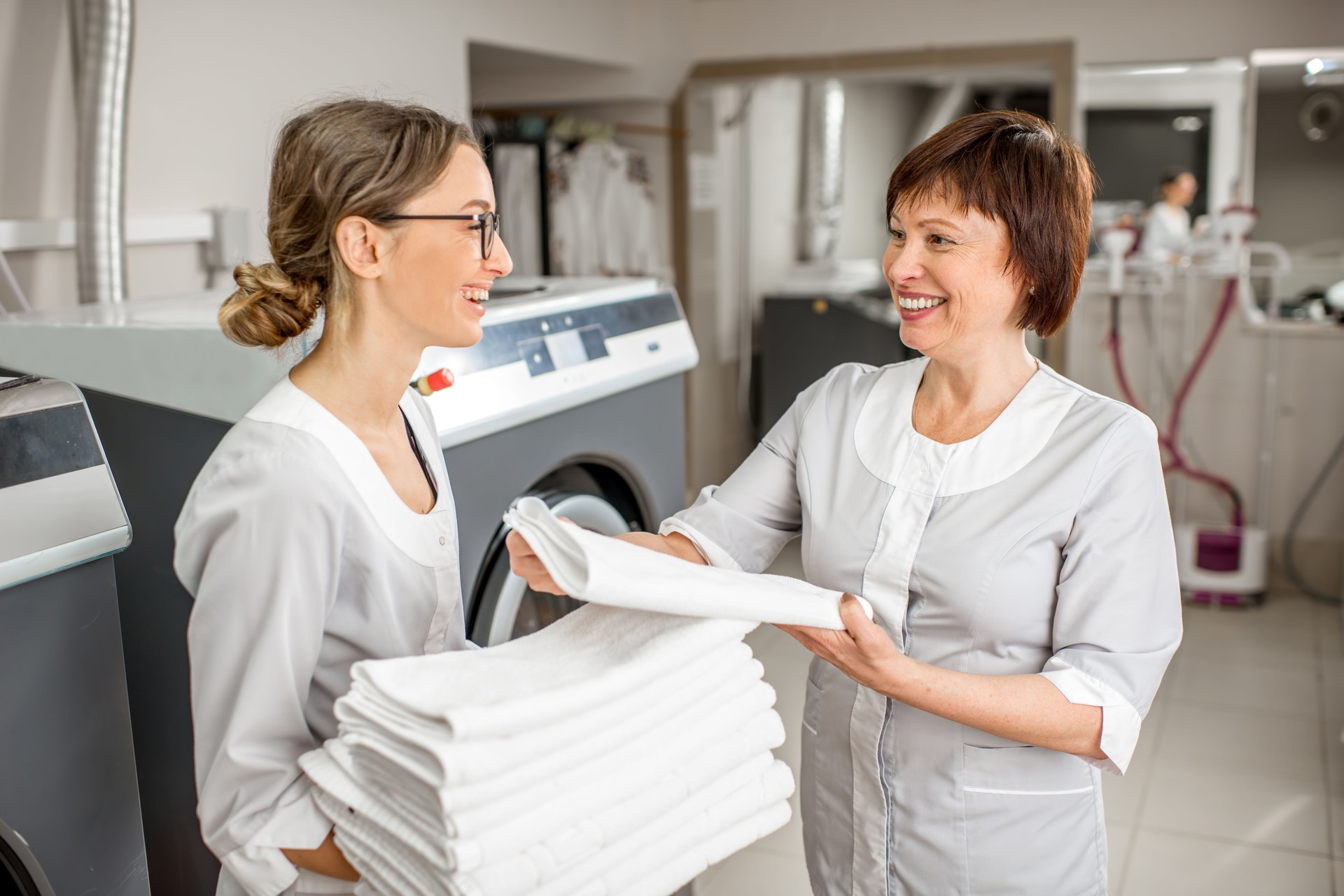 Senior washwoman with young assistant in the laundry